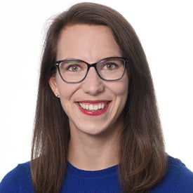 Dr. Rachel Chevalier is smiling and wearing eyeglasses and a blue shirt.