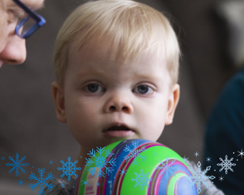 Paxson, a young Children's Mercy patient, holds a striped ball with snowflake imagery overlayed. 