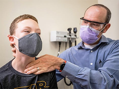Image of Dr. Max Feldt examining neck a pre-teen boy in clinic.