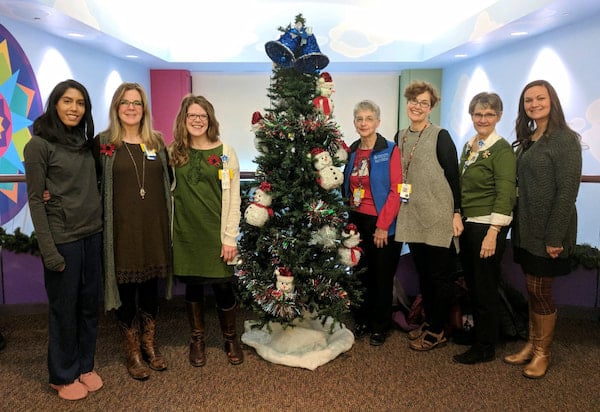 Members of the Hospice Fellowship staff pose together around a Christmas tree.