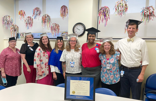 Members of the Hospice Fellowship staff pose together in mortarboard caps.