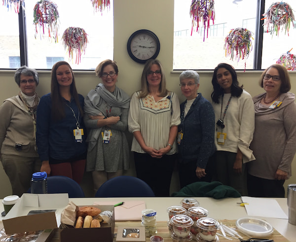 Members of the Hospice Fellowship staff pose together near a table of breakfast foods.