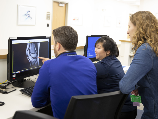 Three Sports Medicine fellows looking at an X-ray of a knee on a computer