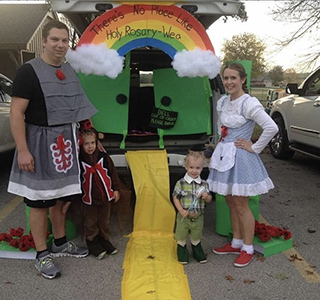 Emily Mccarty, husband and two sons stand at their decorated trunk or treat as Wizard of Oz characters for Halloween.