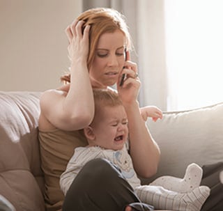 Mom on the phone frustrated while baby is crying