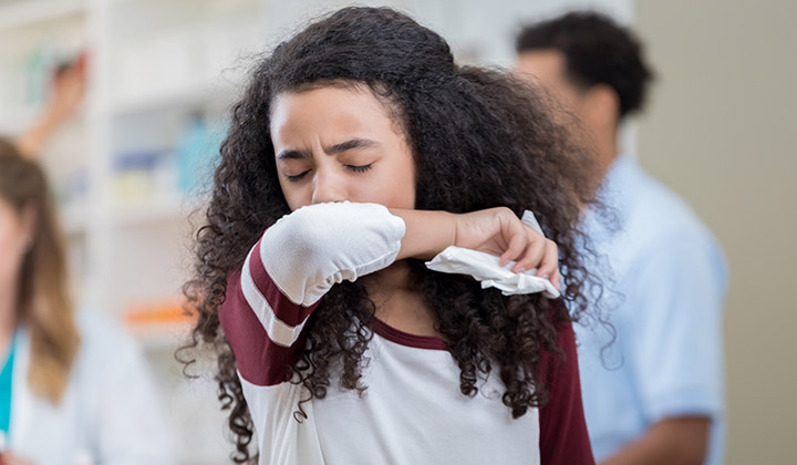 Girl sneezing into elbow