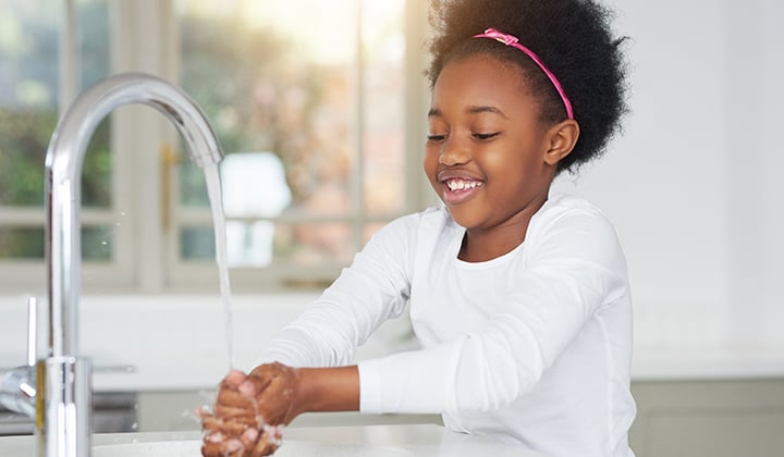 child washing hands at sink