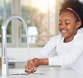 child washing hands at sink