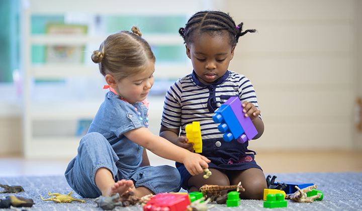 Two young children play lego blocks together. 