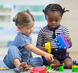 Two young children play lego blocks together. 