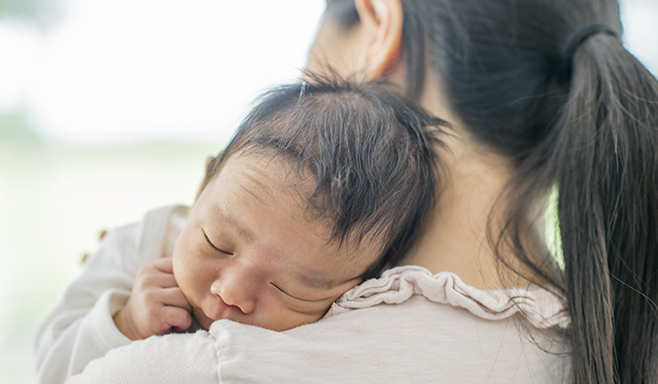 Newborn baby resting on mom's shoulder