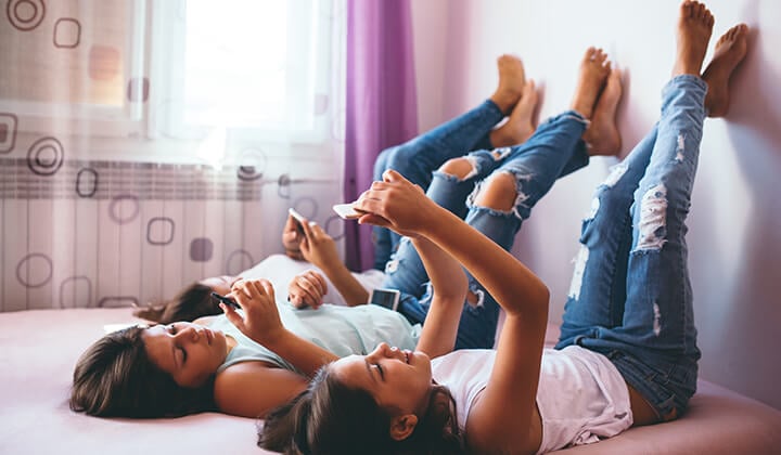 teenage girls lounging and playing on phone