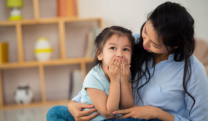 Child covering her mouth while mom looks at her - Parent-ish parenting blog