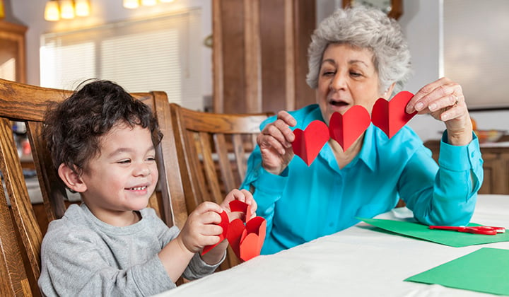 Young boy and grandma cutting heart paper garlands