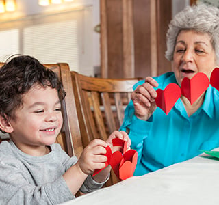 Young boy and grandma cutting heart paper garlands