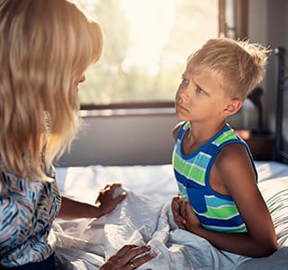 child sick in bed with mom helping