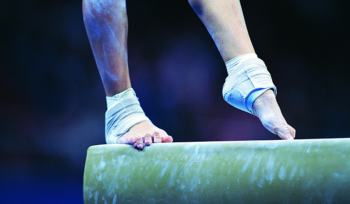 Woman's feet on gymnastic balance beam
