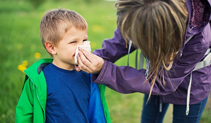 Mom using tissue on son's nose