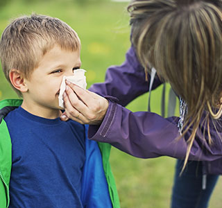 Mom using tissue on son's nose
