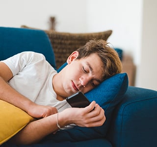 Teenage boy laying on couch with phone
