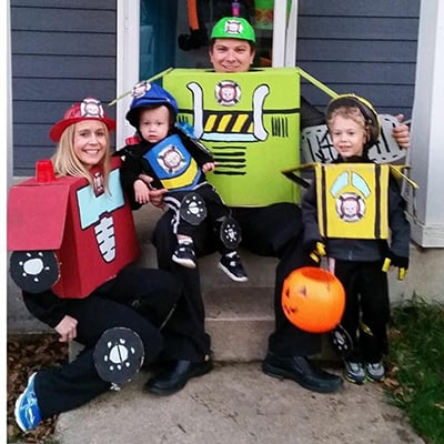 Emily Mccarty, husband and two young sons sit on front porch in Transformer Halloween costumes.