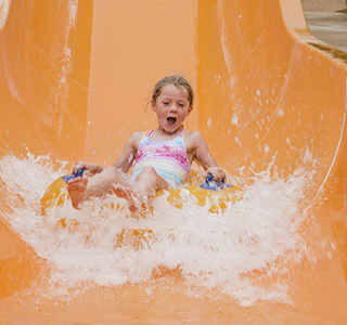 Young girl rides an inflatable tube down a waterpark slide.