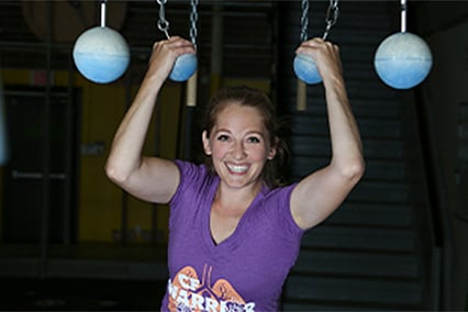 Amber Dawkins smiling and holding balls hanging from chains from the ceiling