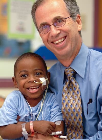 Young black male toddler posing next to Dr. Warady.
