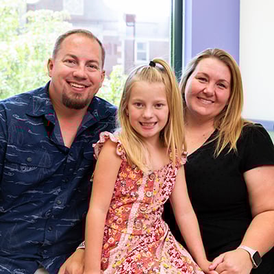 Child sitting between two adults in a hospital room
