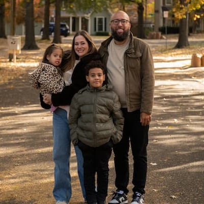 photo of a family posing for photo in the middle of the street with fall background. 