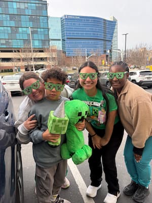 three females in Minecraft glasses standing with young patient 