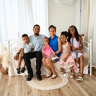 Lilly sits with family members during a family portrait in a bright room.