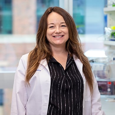 Dr. Alexandra Prosser-Dombrowski stands in a lab wearing a lab coat.