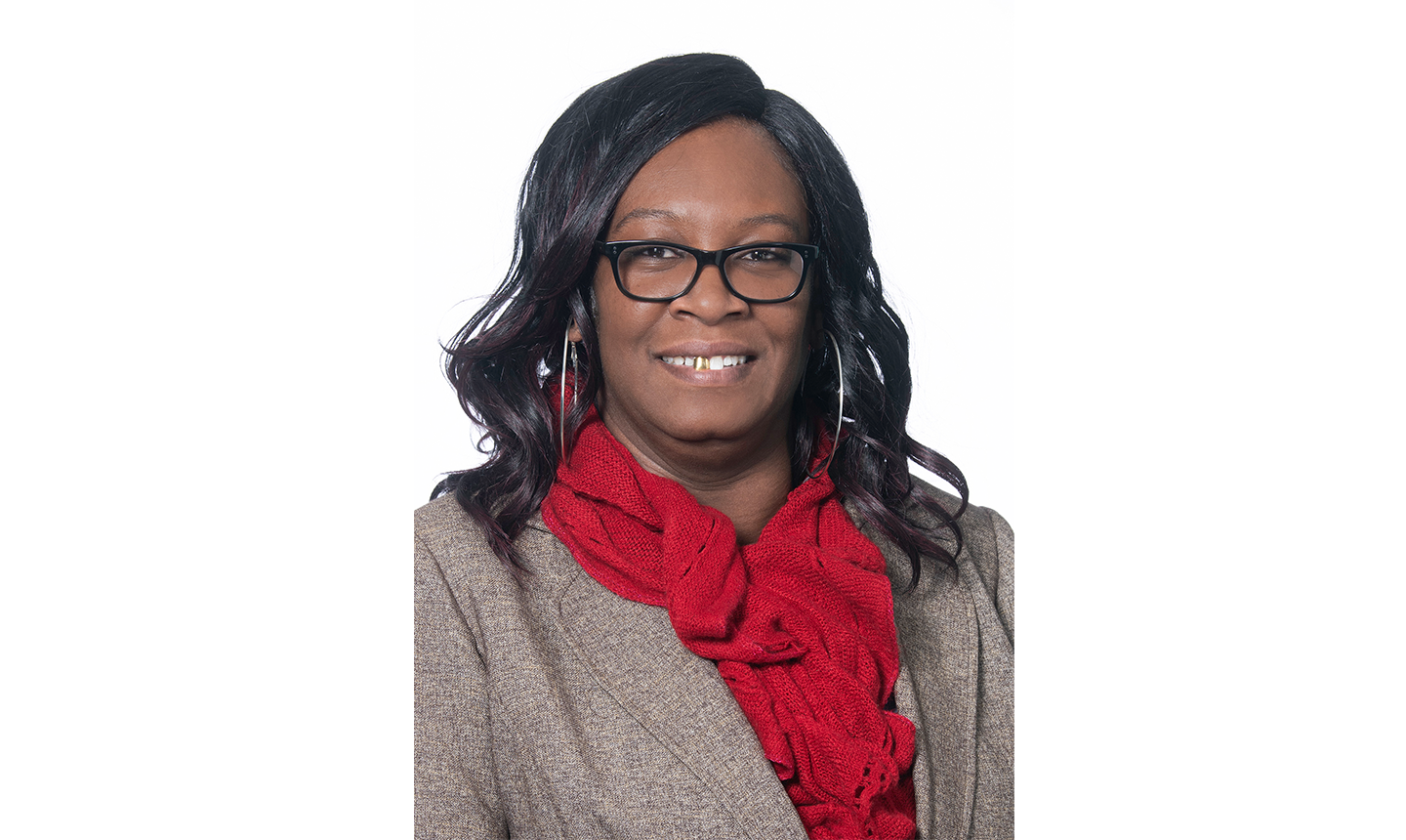 RJ Brooks. She has dark colored hair and is wearing glasses. She is wearing red scarf and a light brown jacket. 