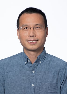 Sheng Xia, vertical photo. He has short black hair and is wearing glasses.