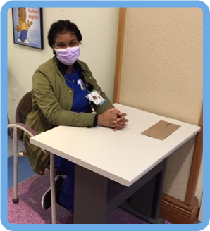 Staff member wearing mask and sitting behind a desk