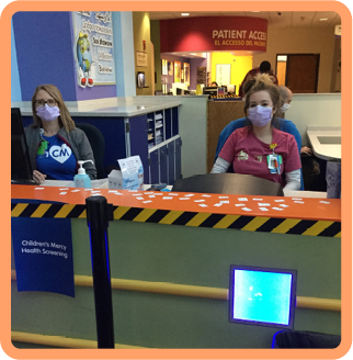 Staff members in face masks sitting behind screening desk