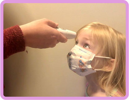 Girl in face mask having her temperature taken