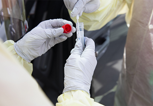 Gloved hands putting a nasal swab in a tube