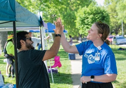A man and a woman high five in a park setting.