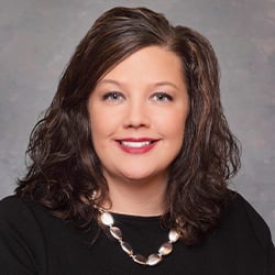 Jennifer Sabree wearing a black top with a silver necklace and smiling.