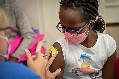 Young girl at Children's Mercy receiving a vaccination in her right arm.
